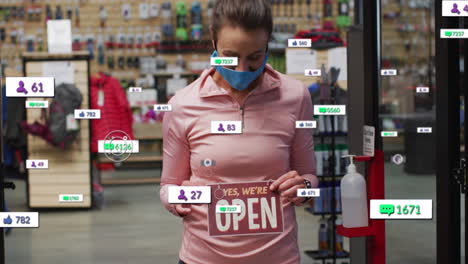 animation of media icons over caucasian female worker with face mask opening shop