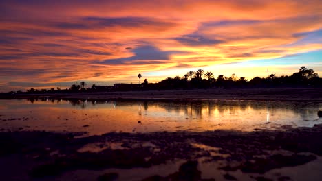 increíble puesta de sol con colores espectaculares en el cielo y las nubes, la imagen se refleja en un lago en medio de la arena en una hermosa playa tropical, lugares vírgenes y paradisíacos