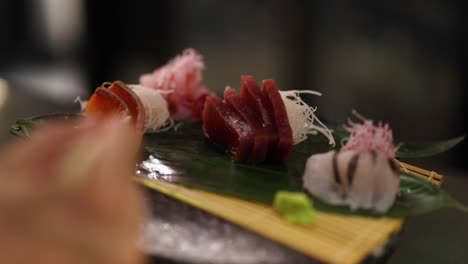 hand picking sushi pieces from a platter