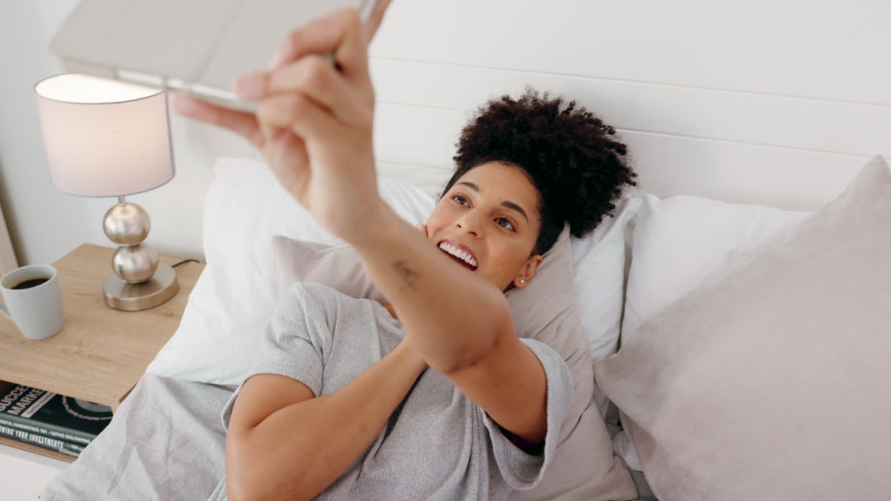 Donna afroamericana, tablet e videochiamata in camera da letto