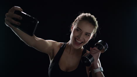 Sport-woman-taking-selfie-photo-with-dumbbell-on-mobile-phone-in-gym