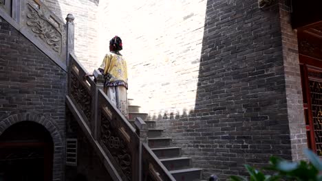 qing dynasty woman with silk dress ascends grey stairs in pingyao, china