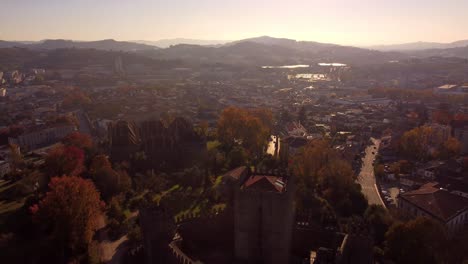 Edificio-Del-Castillo-Medieval-Y-Paisaje-Urbano-De-La-Ciudad-De-Guimaraes-En-Portugal,-Tiro-Aéreo-De-Drones-Durante-La-Puesta-De-Sol