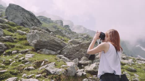 a young woman hiker climbs mountains with photo camera. transfagarasan, carpathian mountains in romania