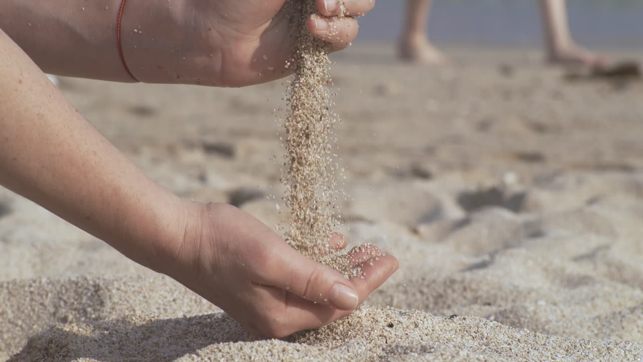 Sand falling from hand in slow motion on a beach. Vacation and travel concept. Shot on super slow motion camera 1000 fps.