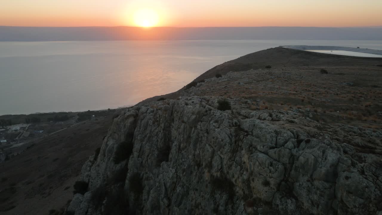 물 위에 아름다운 빛나는 일몰과 함께 가파른 해안 바위 절벽 위에 서사시 드론 샷