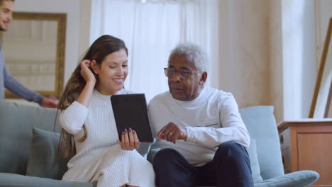 Mujer-Caucásica-Ayudando-A-Su-Abuelo-A-Usar-Una-Tableta.