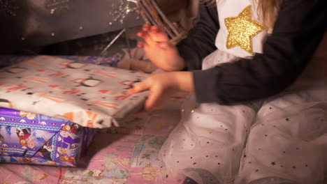 little girl putting self wrapped christmas gift or birthday present by side