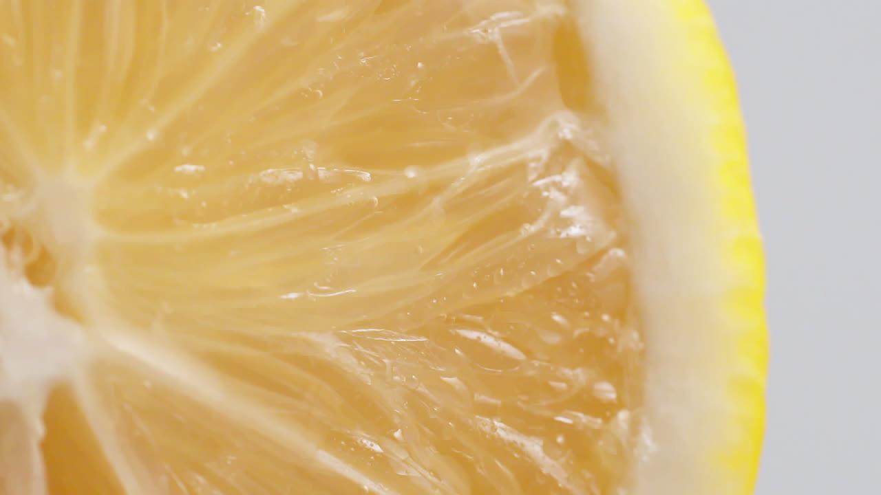 slow motion makro skud af flydende vand fra citron skive på hvid baggrund