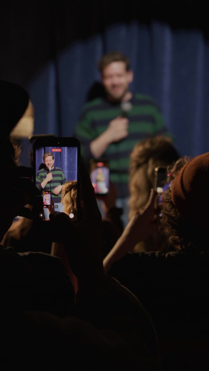 Pubblico che filma un comico che si esibisce in stand-up sul palco con i telefoni