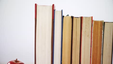 apple and books arranged on wooden table 4k