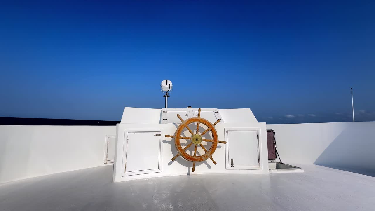 Una scena nautica cinematografica su un ponte di nave bianco, con un classico timone in legno, contro un cielo estivo limpido e blu intenso, catturata da una prospettiva ad angolo basso con luce solare brillante e un'atmosfera serena