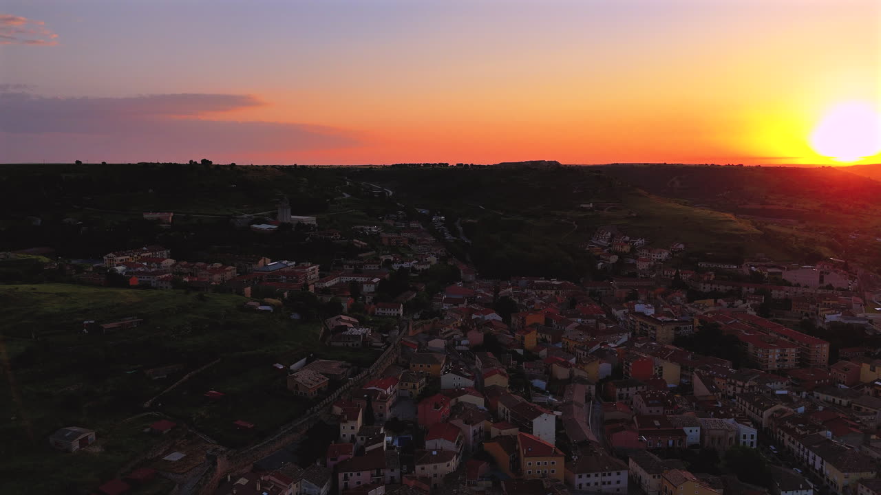 Drone panning shot over Brihuega, La Alcarria, Spain, at sunrise. The skyline, red rooftops, hills and glowing sun create a peaceful and cinematic landscape in warm early morning light