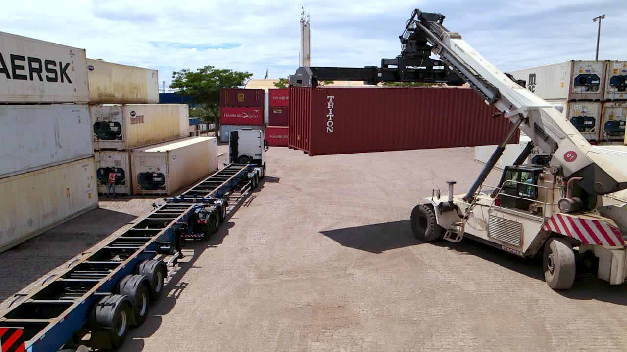Large transoceanic shipping containers moved by crane at boatyard harbor