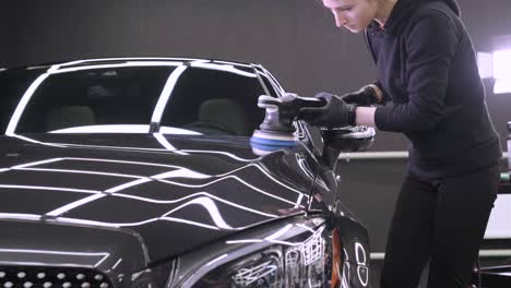 worker polish a black car. car detailing - woman are using machinery car polishers maintenance to remove marks repair according to the surface of the car's paint before contin