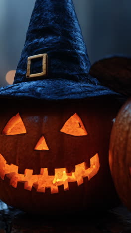 two pumpkins with witch hats on top of a table. the pumpkins are lit up and have a spooky, halloween vibe