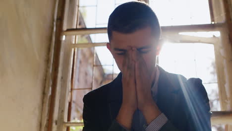 young unhappy businessman sitting on windowsill disappointed