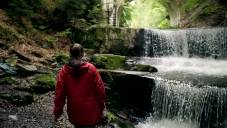 slow motion of a young female tourist enjoying an epic waterfall view.