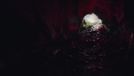 person with red light exploring dark cave