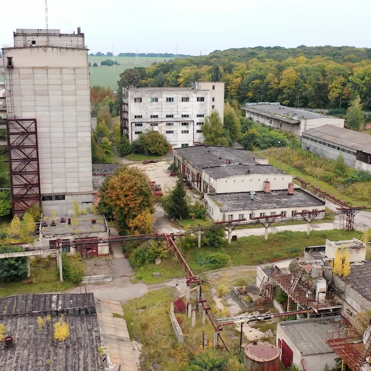 Abandoned factory with many ruined buildings. Old brick thick pipe on empty plant. Deserted industrial territory. Aerial view
