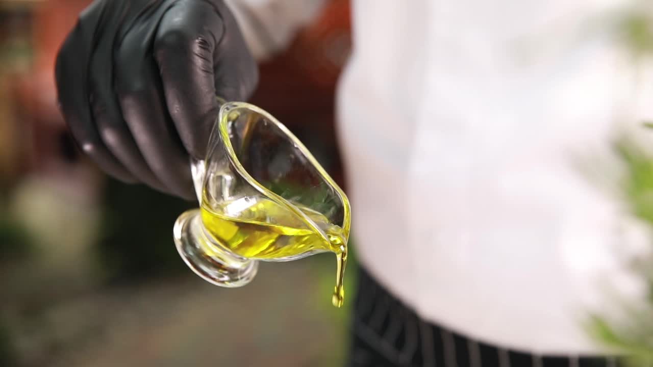 шеф-повар наливает оливковое масло