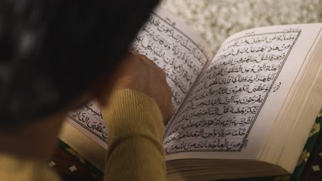 close up of muslim man at home sitting on floor and reciting from the quran 2