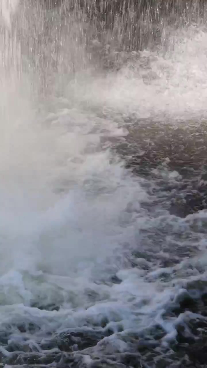 Potente cascata si getta in acque bianche vorticose, creando nebbia e movimento dinamico alla luce naturale del giorno.