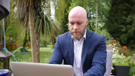 a man working from home on a laptop computer in his garden