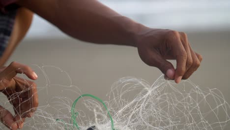 primer plano de las manos desenredando una red de pesca