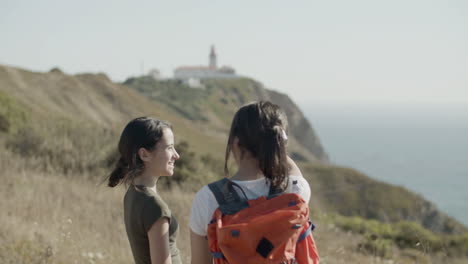 two girls standing on mountain cliff, enjoying stunning sea view