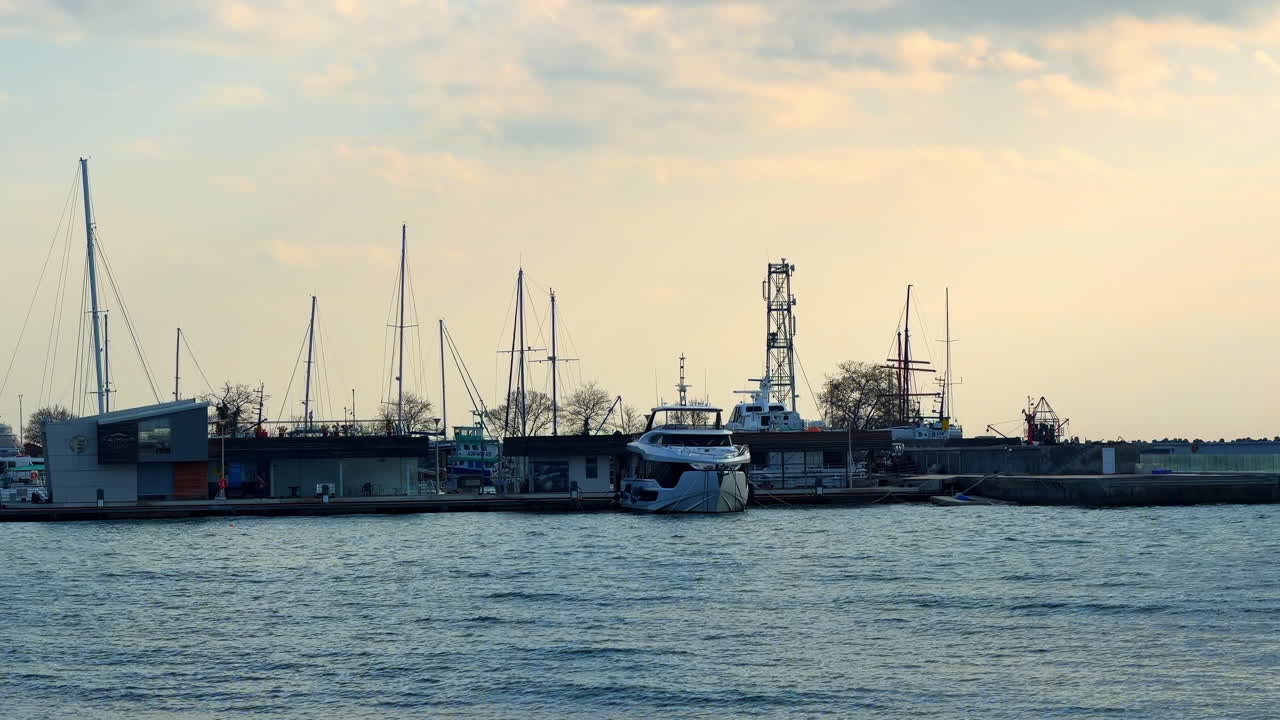 Burgas, Bulgarien, 29. Oktober 2025: Boote, die am späten Nachmittag in der Nähe der Küstenlinie im Hafen angedockt haben. Boote parken im Hafen, während die Sonne hinter den Gebäuden am Wasser untergeht.