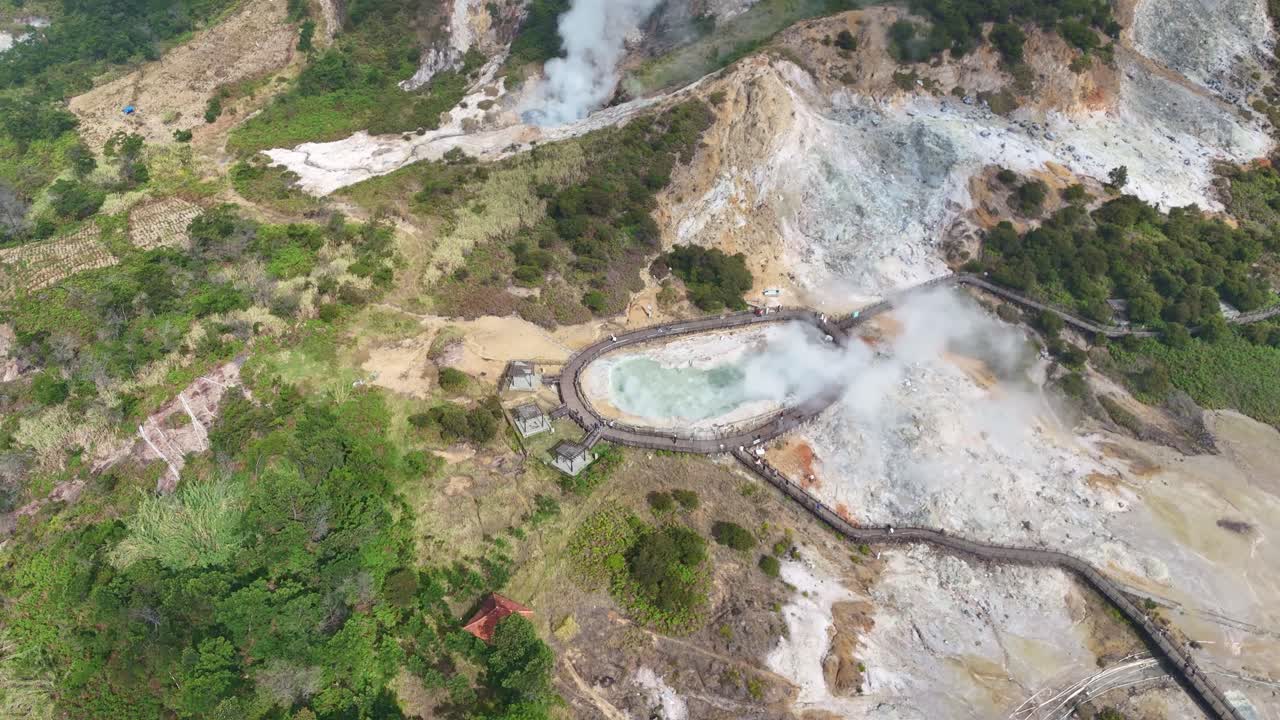 Aerial view of Sikidang Crater in Dieng Plateau, Central Java, Indonesia, showing steaming geothermal pools surrounded by volcanic landscape and lush greenery