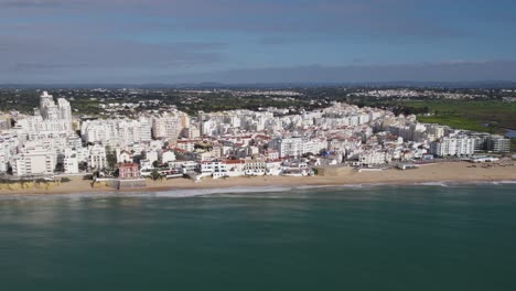 Luftaufnahme-Des-Strandes-Armacao-De-Pera-Mit-Weißen-Gebäuden-Im-Hintergrund