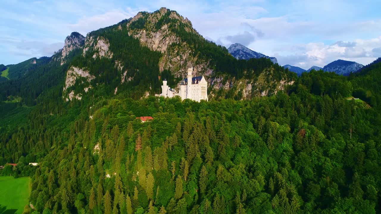 Neuschwanstein Castle stands majestically atop forested hill in Bavaria, Germany