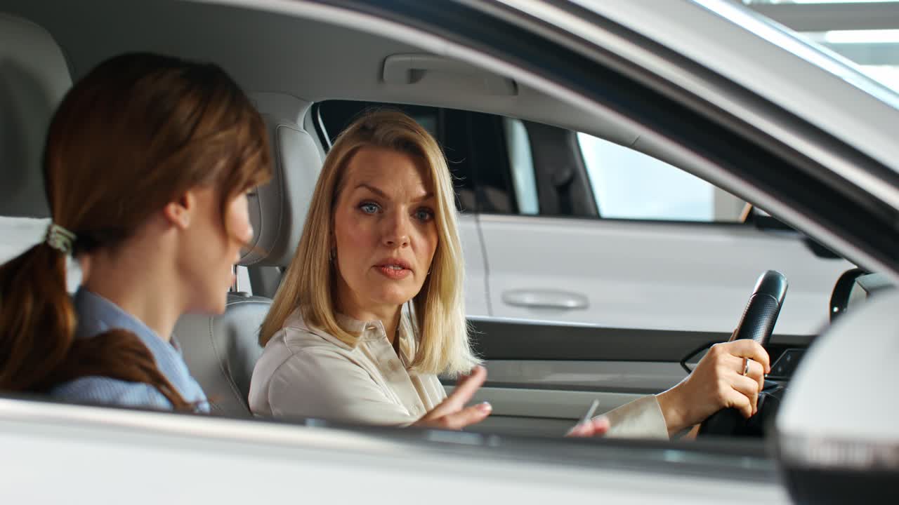 Two women discussing a car in a showroom