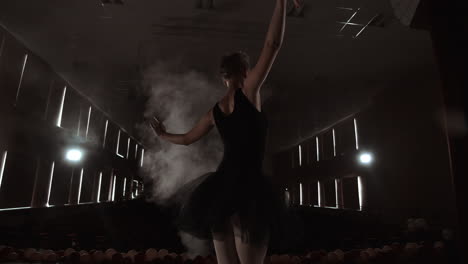 Ballerina-is-practicing-her-moves-in-dark-studio.-Young-girl-dancing-with-air-white-dress-tutu-spinning-around-and-smiling.-Gracefulness-and-tenderness-in-every-movement