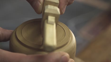 a potter cuts a circle of clay with a compass