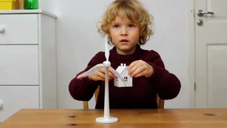 child playing with wind turbine and house model