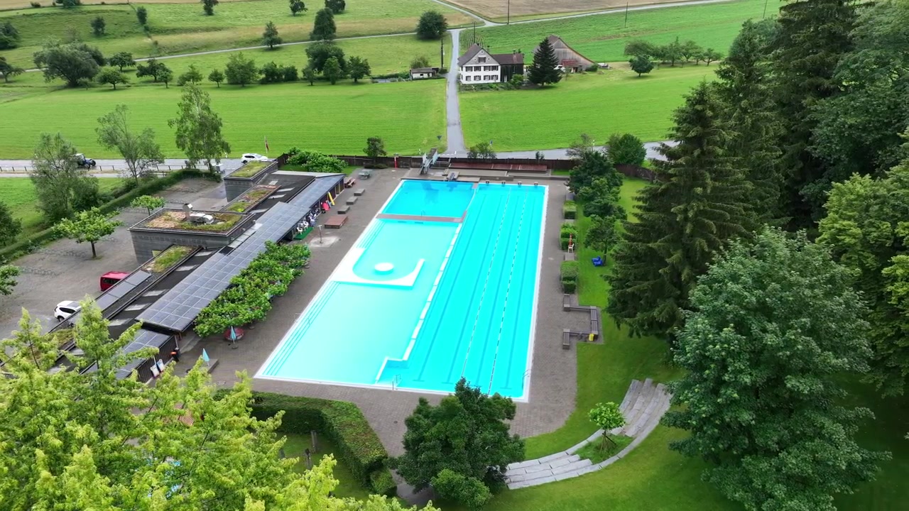 Forladt swimmingpool i et smukt natur- og grønt landskab, levende farver. Droneudsigt.
