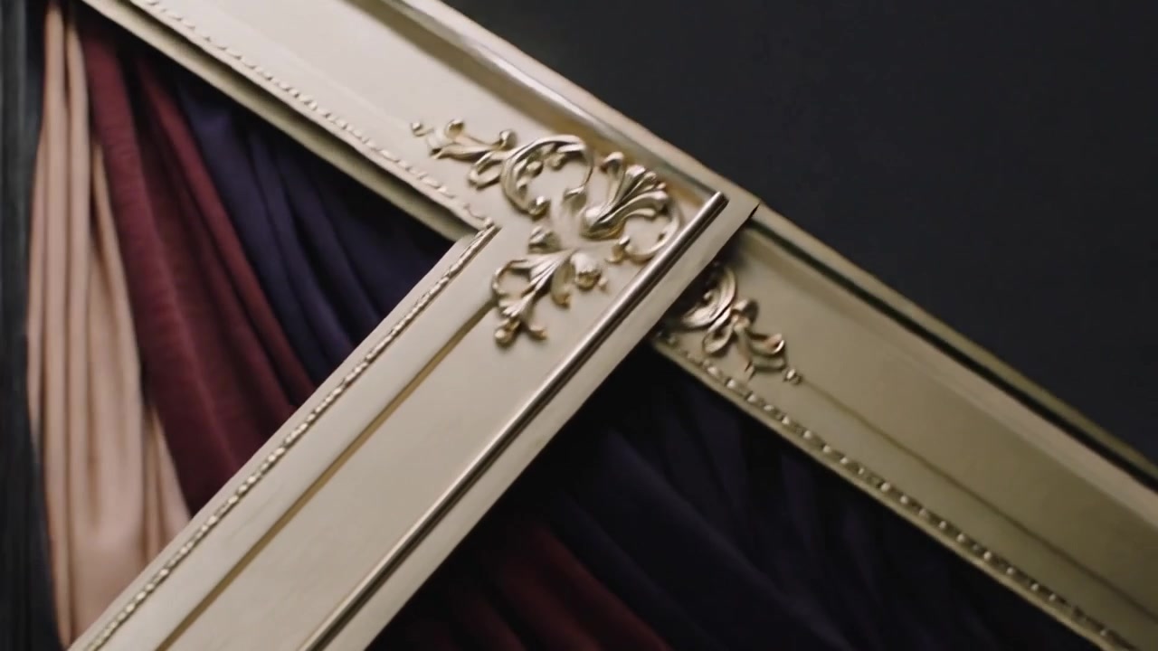 Telecamera panoramica che rivela cornici dorate ornate che si incrociano in diagonale su una parete della galleria, esponendo un drappeggio.