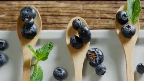 Spoons-of-blueberries-with-mint-arranged-on-tray-table-4k