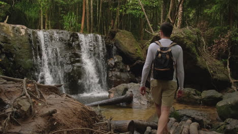 man hiking through a tropical waterfall