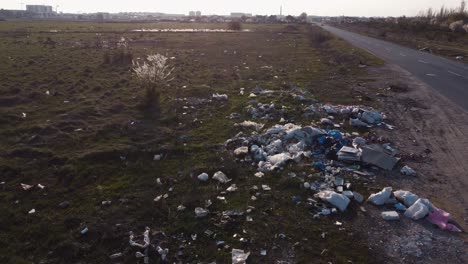 field full of industrial and domestic garbage near city road