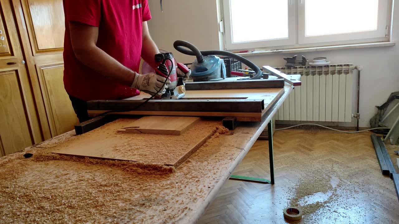 Flattening wood with milling router machine in small woodworker workshop at home
