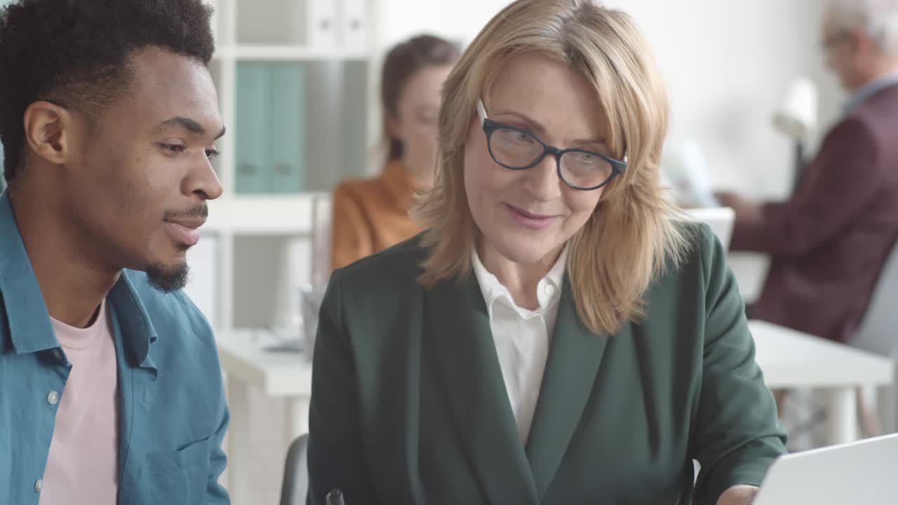 gerente experimentada que orienta a un aprendiz afroamericano en la oficina