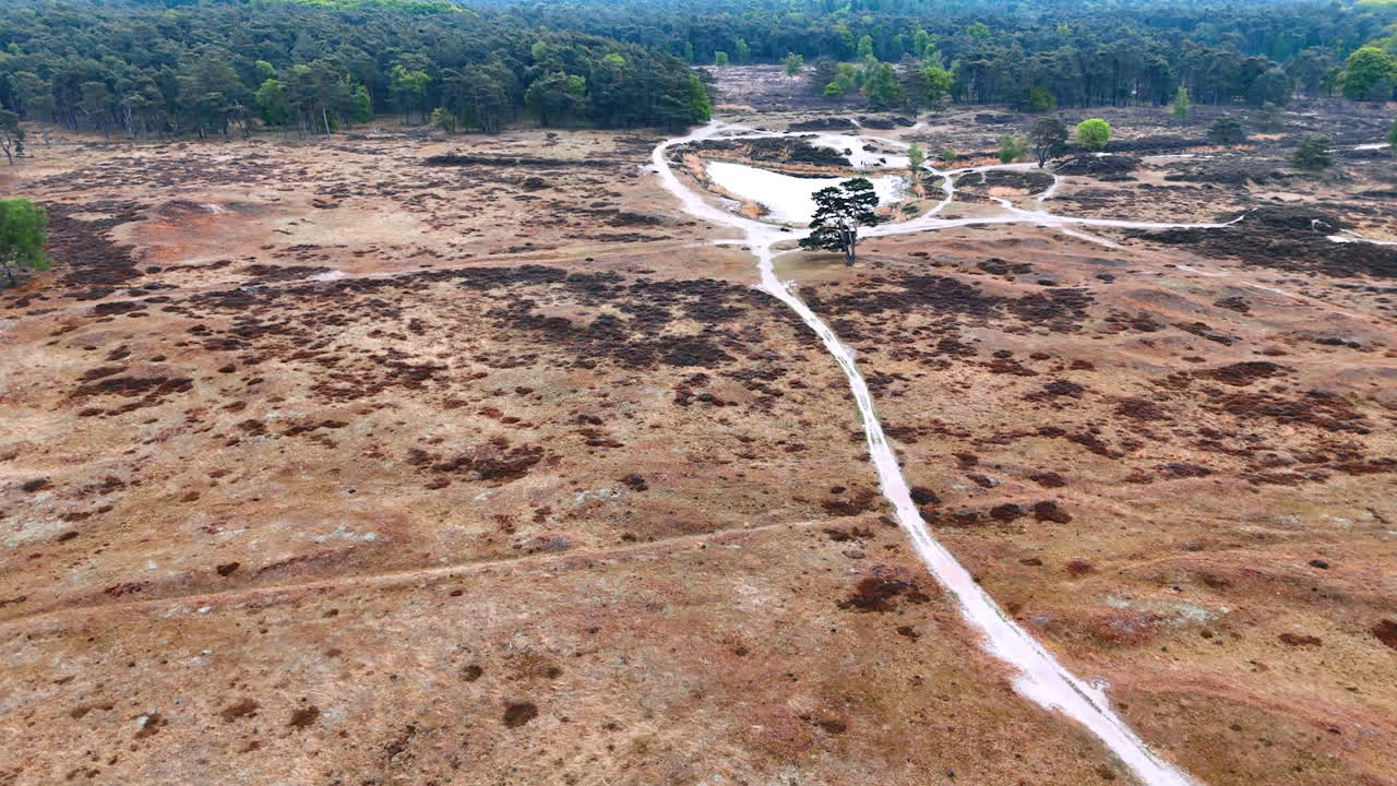 People at the path where water used to flow. Drone footage over the dry area approaching the little pond surrounded by the forests.