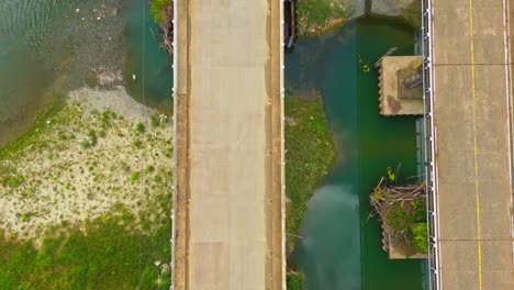 raised highway crossing daywan river with passing vehicles near the municipality of claver in surigao del norte in the philippines, aerial top down shot