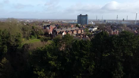 vista aérea sobre los árboles del parque al paisaje urbano industrial con rascacielos azules en el centro, merseyside, inglaterra