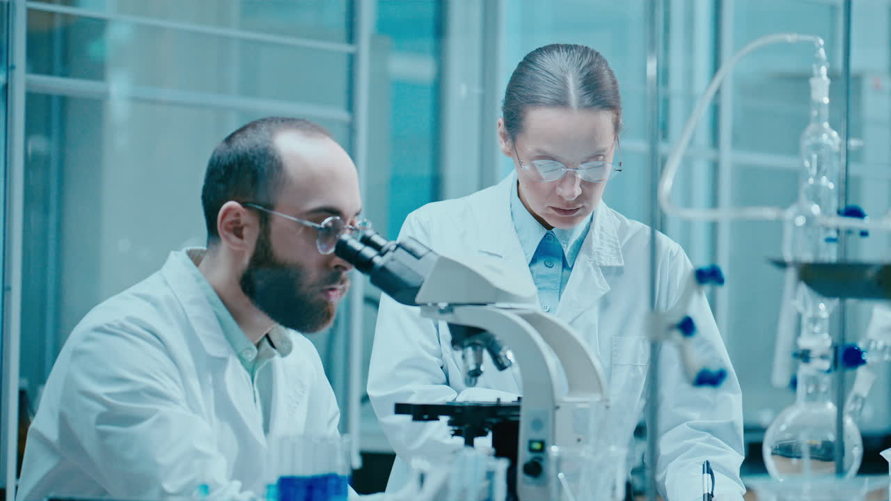 Male and Female Scientists Collaborating during Microscopic Research in Lab