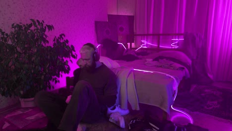 hombre escuchando música en un dormitorio iluminado con neón púrpura